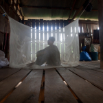 Man under net in camp for migrant cassava farmers