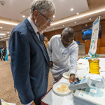 Bill Gates observes a device at the Innovation Tech & Science Fair in Abuja
