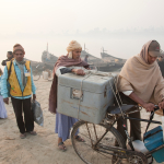 Polio vaccination team members carry cold box on bicycle
