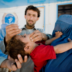 Health worker vaccinates child against polio